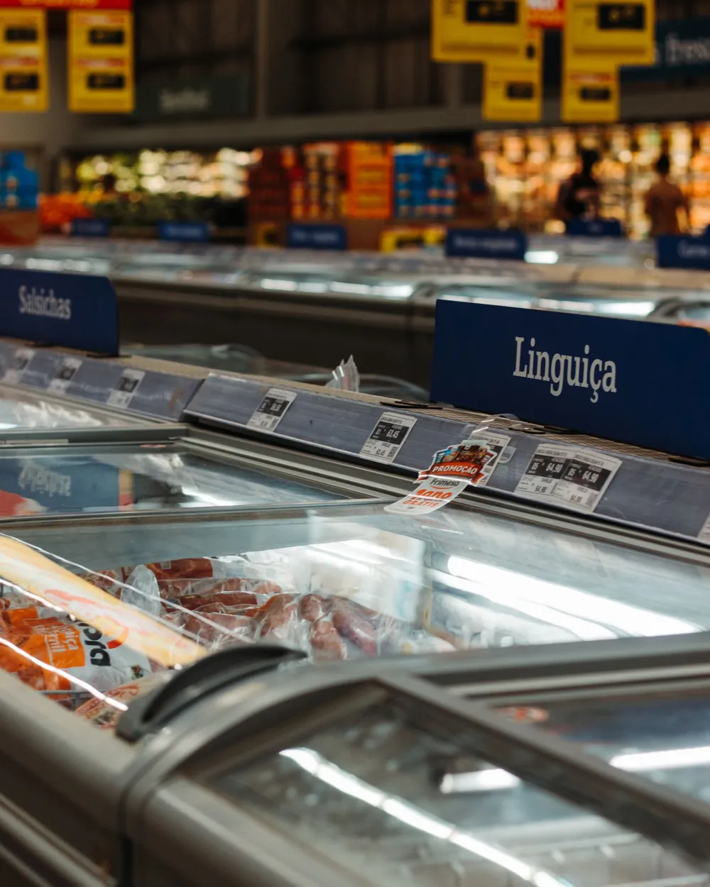 Ilhas de freezer de um supermercado, com placas de linguiça e salsicha
